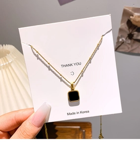 Detailed close-up of a square black pendant on a 18k gold plated stainless steel bead chain