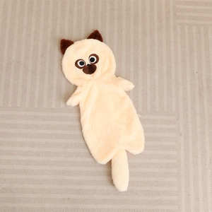 Cream plush cat unstuffed shell with brown ears and long tail on a beige textured rug