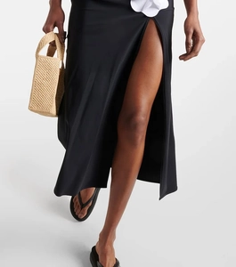 Detail of high-slit black maxi skirt with 3D white floral applique on the waist