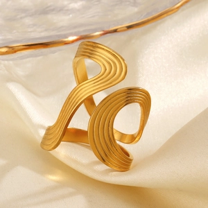 Golden irregular wavy geometric ring on white silk background with elegant glass plate