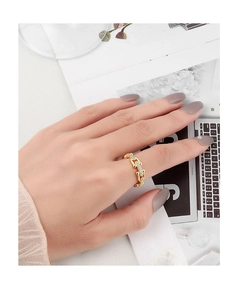 Detailed view of a gold chain ring with sparkling micro-inlay stones worn on a hand