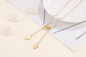 Détail d'un collier doré à cœur coulissant avec pendentifs garçon et fille au style épuré