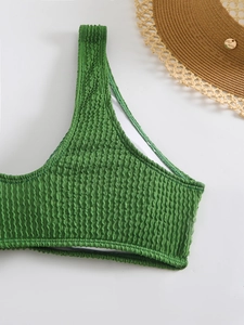 Detail shot of emerald green crinkle texture bikini top with woven straw hat background