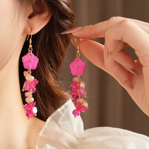 Détail de boucles d'oreilles fleurs roses avec perles et cristaux sur mannequin