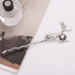 Macro detail of vintage silver flower hair pin with leaf accents and a white pearl bead