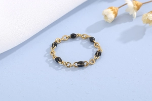Dettaglio dell'anello a catena dorata con perle ovali nere su sfondo azzurro