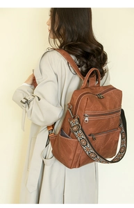 Detail of vintage brown leather backpack with woven strap and multiple zipper pockets