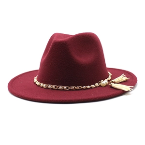 Detail of wool fedora hat with pearl tassels and golden chain on deep burgundy felt