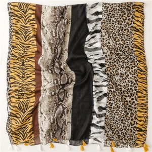 Close-up of zebra and leopard print scarf fabric texture with decorative yellow tassels