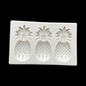 Detailed white silicone mold with three pineapple-shaped cavities on black background