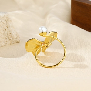 Close-up of gold flower petal ring with center pearl on minimalist band setting