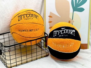 Detail of plush basketball pillows with OFFCOURT HUSTLE embroidery on white fabric
