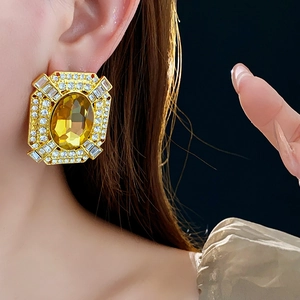 Dettaglio di orecchini vintage in oro con gemma gialla e cristalli scintillanti