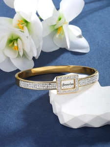 Macro shot of gold bracelet with pavé rhinestones and Forever Love engraving detail