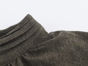 Macro shot of the ribbed neckline on a high-quality dark olive green knit dress