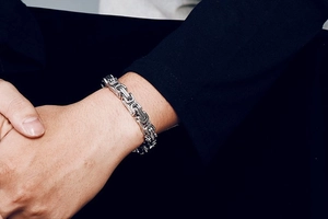 Detailed close-up of thick silver Byzantine chain bracelet in polished stainless steel