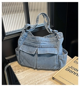 Detail of light blue denim tote bag with large front pockets on stone surface