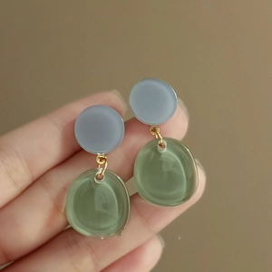 Detail of color-block resin earrings in grey-blue and translucent green on gold links