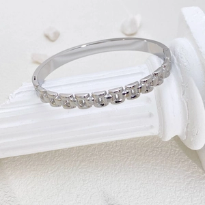 Eleganter Gliederarmband aus Titanstahl in Silber auf einer dekorativen weißen Säulenbasis