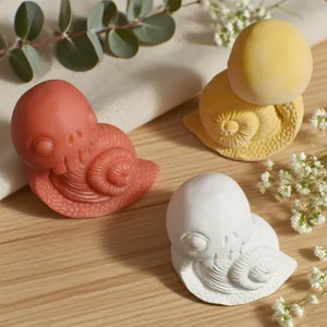 Tre statuine creative a forma di lumaca teschio in bianco, giallo e rosso su tavolo in legno