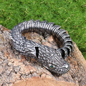 Detail of vintage snake scales bracelet with green eyes on rustic wooden bark