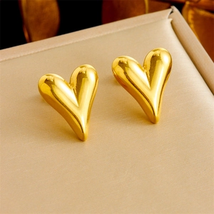 Elegant gold heart stud earrings for women on a textured jewelry display box