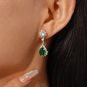 Close-up of elegant pear-shaped green zircon earring with halo setting on a model