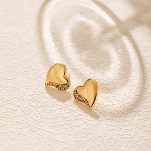 Polished heart stud earrings with colorful zircon stones on white textured surface