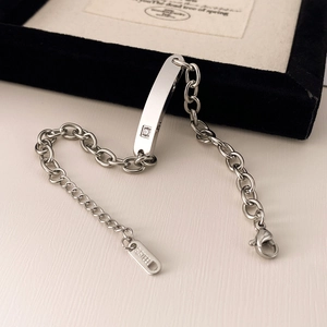 Detailed macro view of silver stainless steel curb chain with engraved ID plate and zircon