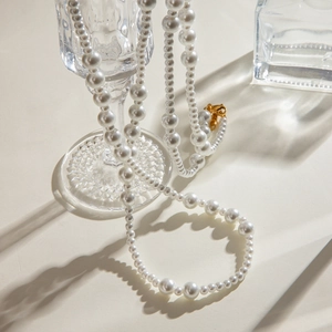 18K gold stainless steel necklace with gradient white pearls draped over a glass