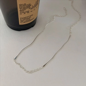 Minimalist 925 sterling silver necklace with irregular wave bar on white background