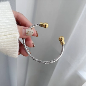 Detail of silver twisted wire bracelet with gold ball ends held over white fabric