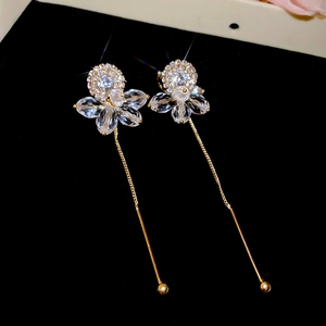 Detail of gold tassel earrings featuring crystal flower studs and long chain fringes