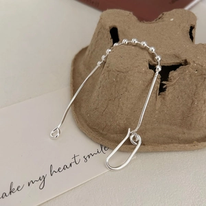Macro shot of minimalist silver long bar U-shaped earrings on brown paper card stand