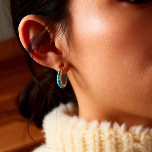 Detailed view of vintage gold-plated hoop earrings with turquoise and white stones