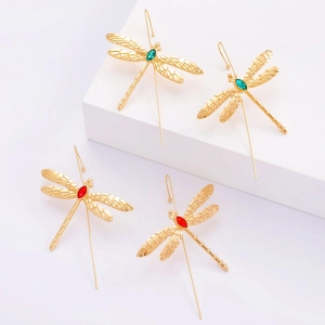 Boucles d'oreilles libellule dorées avec gemmes rouges et vertes sur socle blanc
