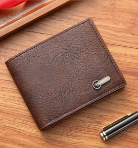 Gros plan du portefeuille en cuir marron avec texture litchi et logo en métal bleu gemme