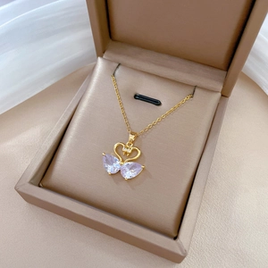 Detail of a gold swan pendant featuring purple drop-shaped crystals in a jewelry box