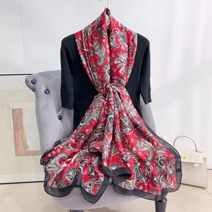 Detailed view of soft red paisley silk scarf with black sheer trim draped on chair