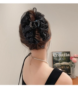 Détail d'une pince à cheveux élégante en dentelle à pois noirs sur un chignon bas