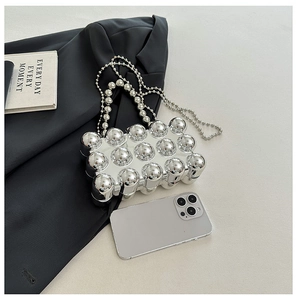 Detail view of silver metallic acrylic crossbody box bag with bubbly texture on a blazer