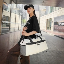 White canvas fitness bag with black handles and side mesh pocket shown in outdoor setting