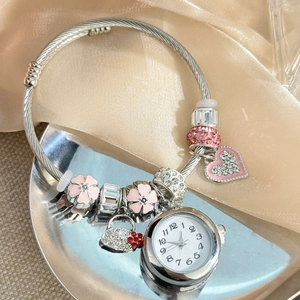 Detailed macro view of silver beaded charm bracelet watch with pink floral pendants