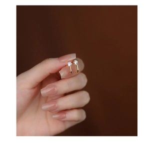 Detail of s925 silver curved gold earring with a clear round zircon stone held by hand