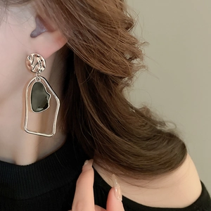 Vue détaillée de boucles d'oreilles géométriques asymétriques dorées portées par un mannequin