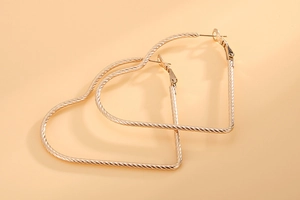 Detailed view of large gold twisted heart hoop earrings with textured stainless steel finish