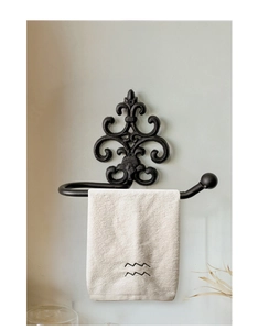 Detail of vintage cast iron towel rack with black fleur-de-lis relief on a wall