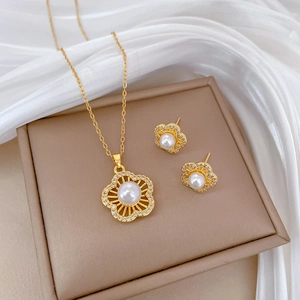 Macro shot of gold floral jewelry set with pearls and rhinestones on white silk
