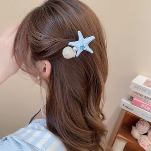 Detail of starfish hair clip with blue rhinestones, white shell, and pearl on model