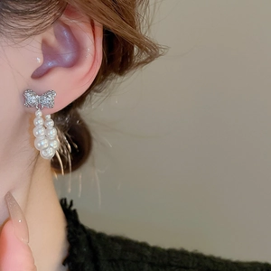 Close-up of bow knot earrings with sparkling rhinestones and elegant faux pearl tassels